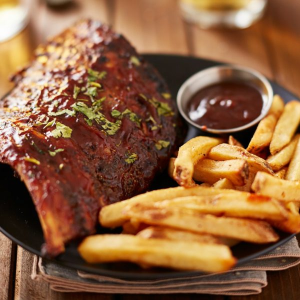 half rack of barbecue pork ribs with french fries on plate